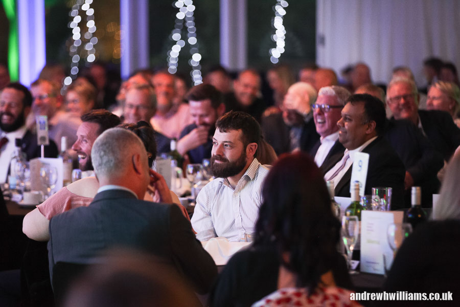 Photography of dinner reception attendee enjoying the presentation